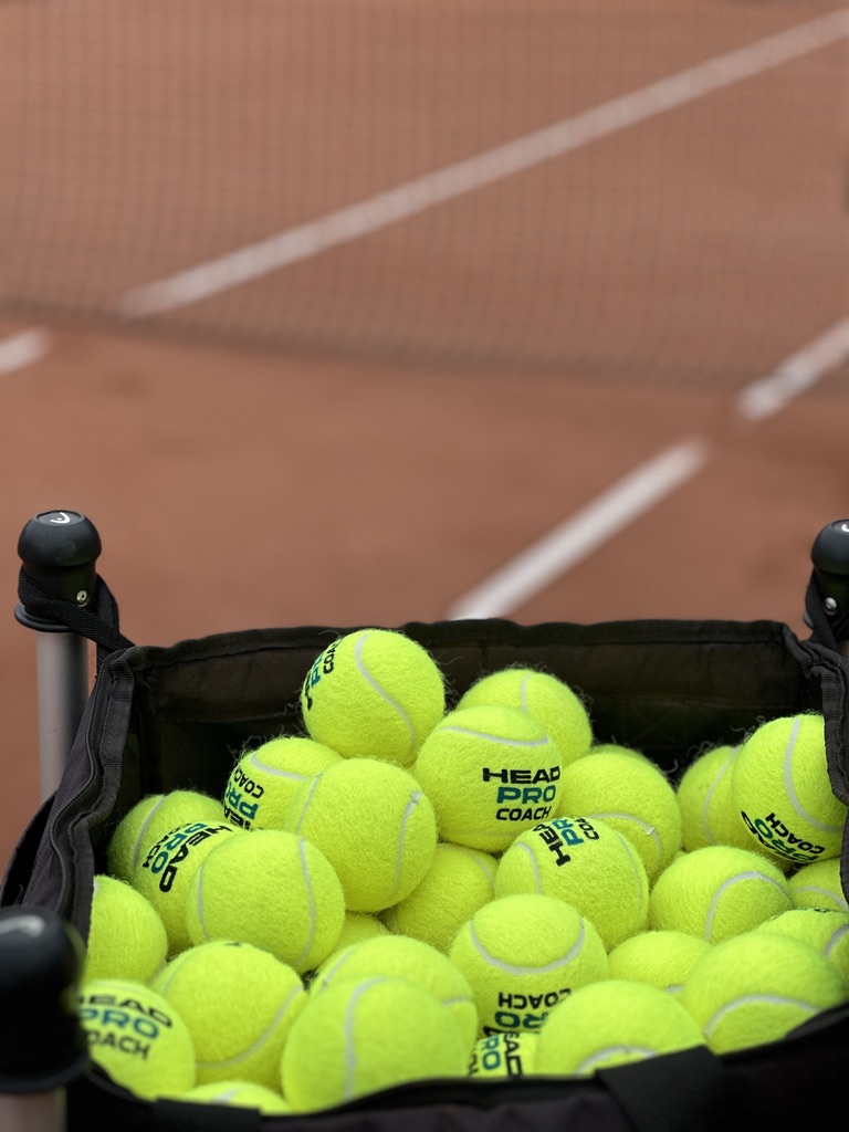 Trainingskorb mit Tennisbällen auf Sandplatz – Tenniscamp und Training in Düsseldorf